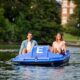 Happy friends pedal boating on river in city
